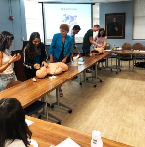 A group of people stand with rubber CPR dummies