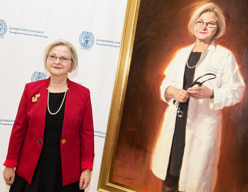 Dr. Toporowicz stands next to her portrait