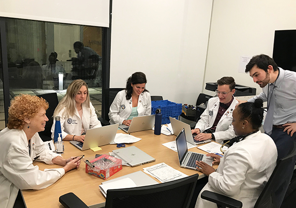 A group of doctors and medical students confer around a table