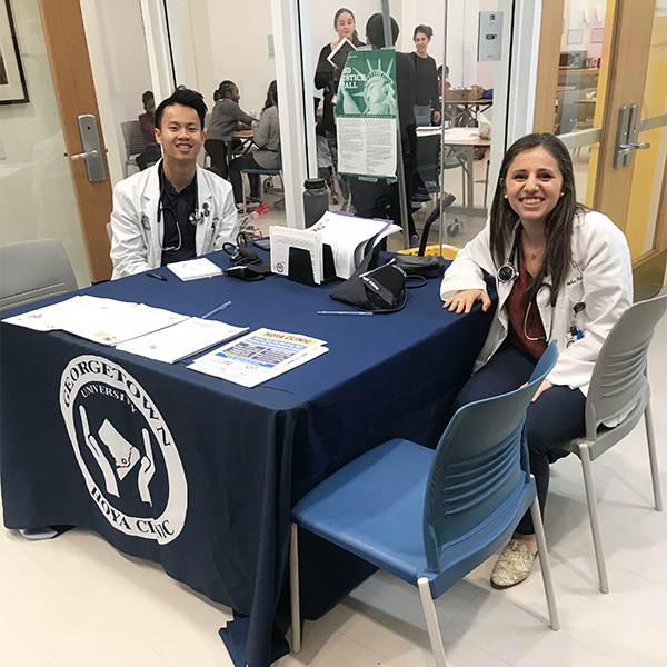 Two medical students sit at a table in the building lobby