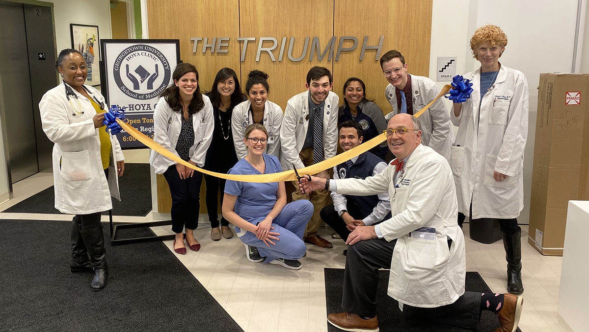 A group of people pose together at a ceremonial ribbon-cutting at The Triumph shelter