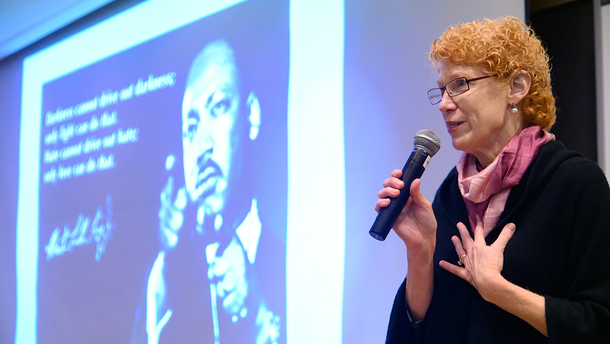 Eileen Moore speaks before a screen on which an image of Martin Luther King Jr. is projected