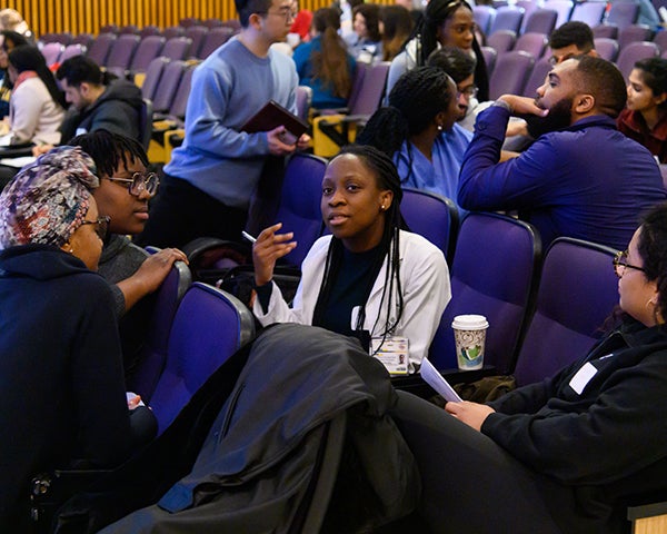 Groups of students talk in an auditorium