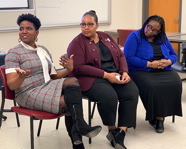 Three women sit side by side in chairs