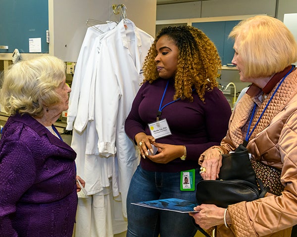 Three women talk together in a lab