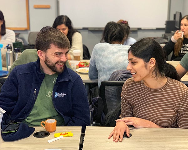 Blake Hite and Nitika Gupta talk with each other amid tables of classmates.