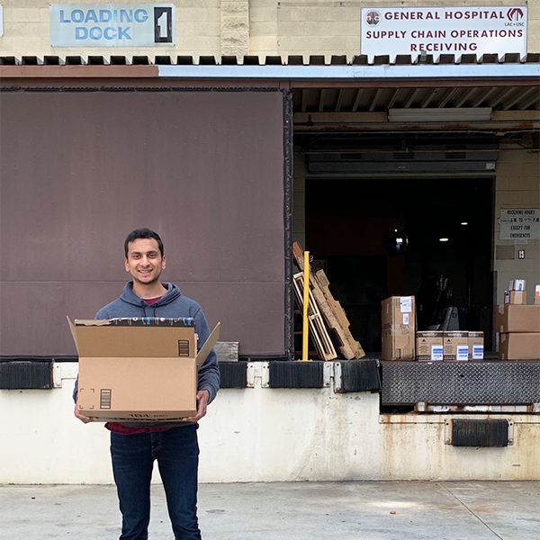 Lavan Rajan holds a box of supplies outside a hospital loading dock