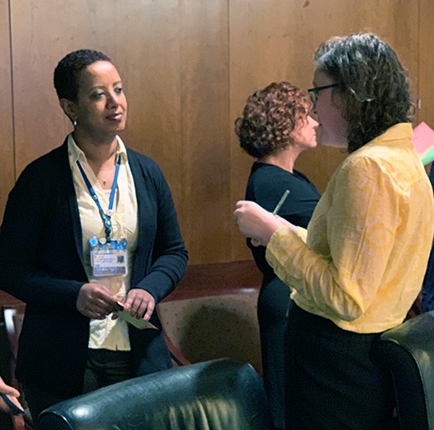 Two women talk; another woman stands in the background