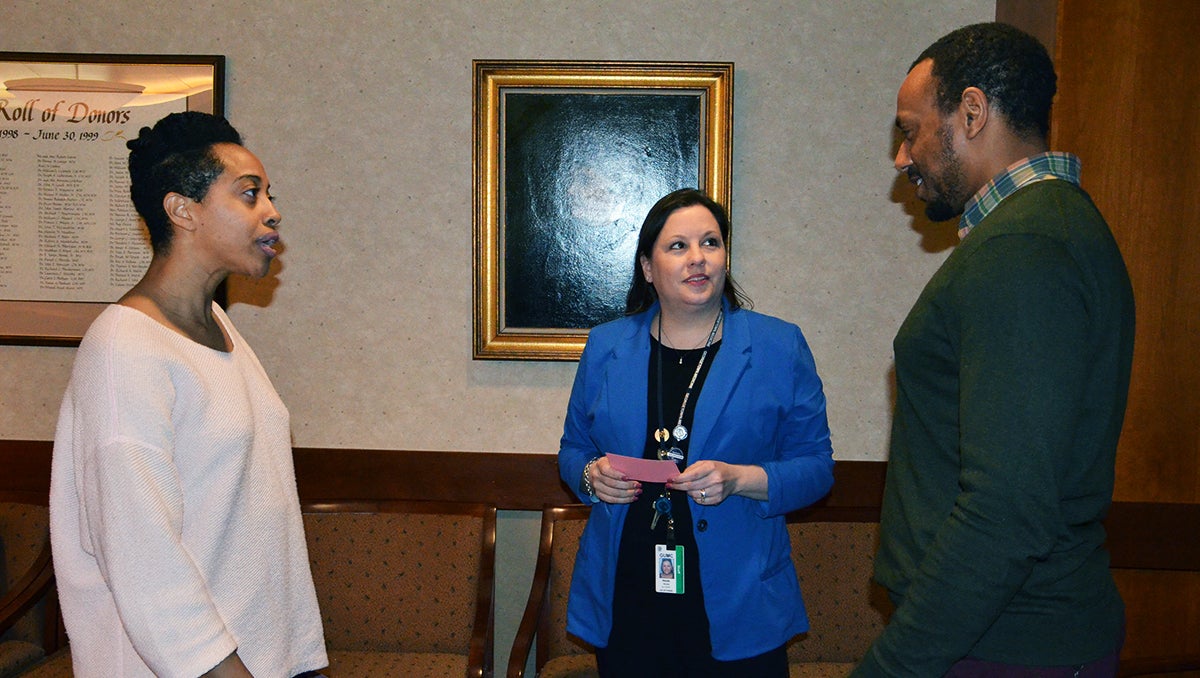 Three people stand together and talk