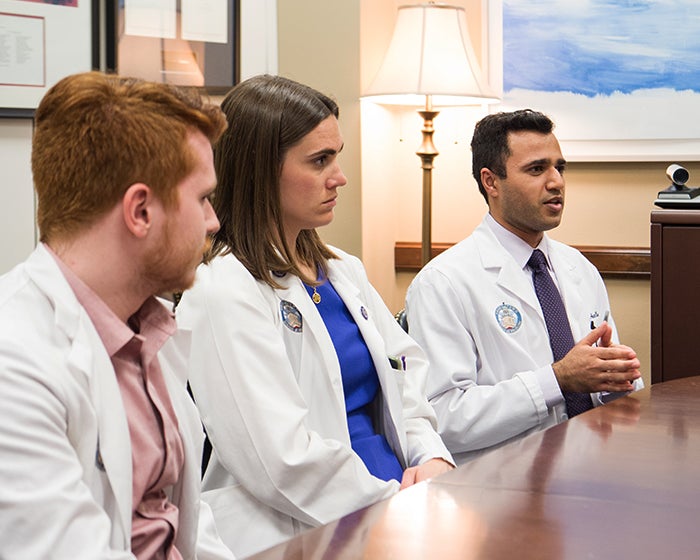 Three medical students sit at a table in a congressional office