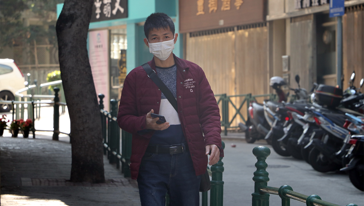 A man wearing a mask walks down an empty street in Macau, China