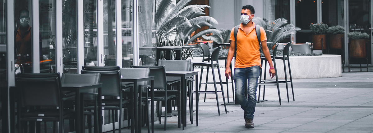 A man wearing a mask walks an empty street