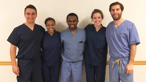 A group of medical students in scrubs stand together for a group photo