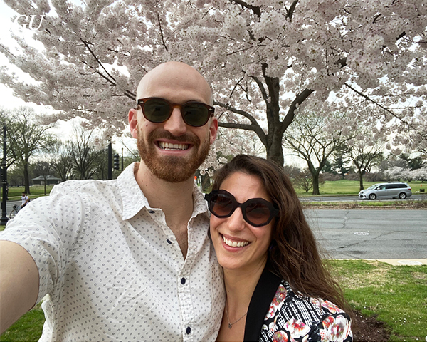 Two people embrace under cherry trees