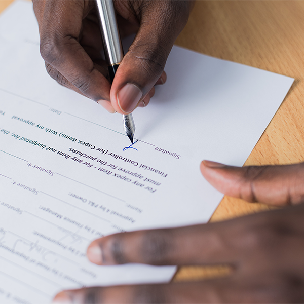 Hands signing a paper with a pen