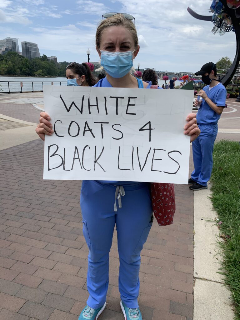 Sarah Trent (M'22) holding a sign that reads "White coats 4 black lives"