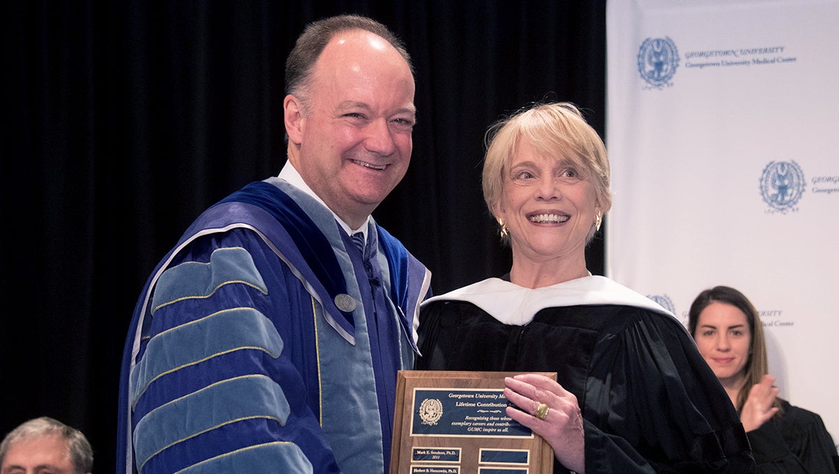 Jack DeGioia hands Victoria Jennings a plaque at Convocation 2016