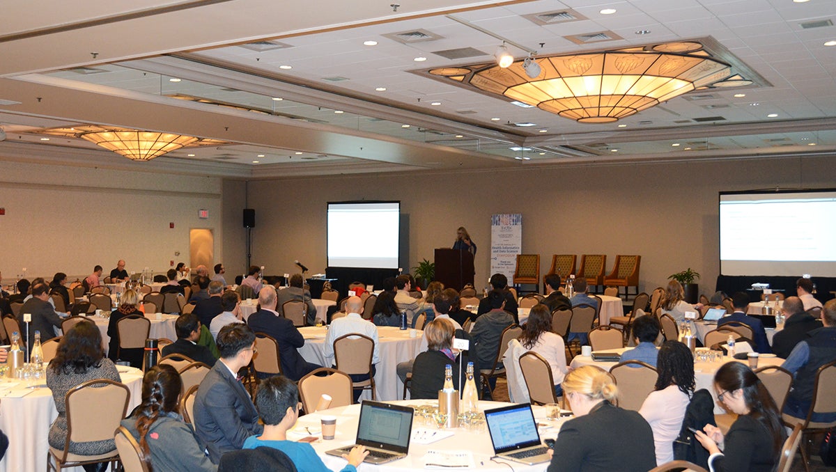 A conference room full of people listening to a speaker