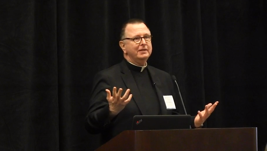Fr. Myles Sheehan speaks at a podium