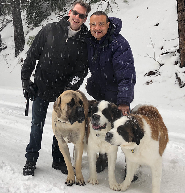 Flynn and Jones hold leads for three large dogs in the snow