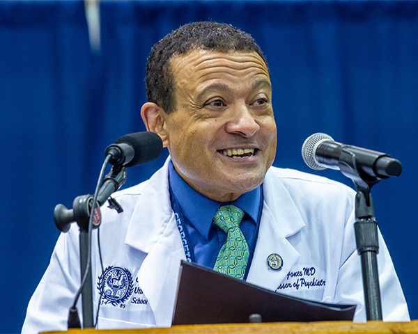 Dean Jones speaks at a podium during White Coat