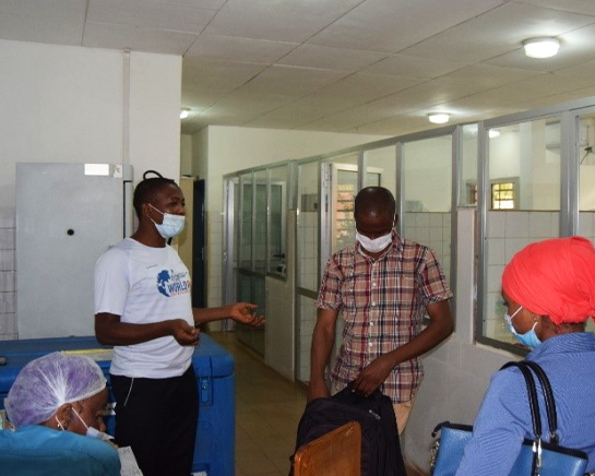 Four people wearing protective masks have a discussion in a hospital hallway