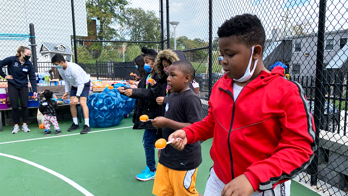 Children balance plastic eggs on plastic spoons in preparation for a race down a tennis court in DC