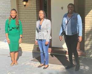 Three individuals, including Dr. Seliby Perkins, stand outside the Sasha Bruce House