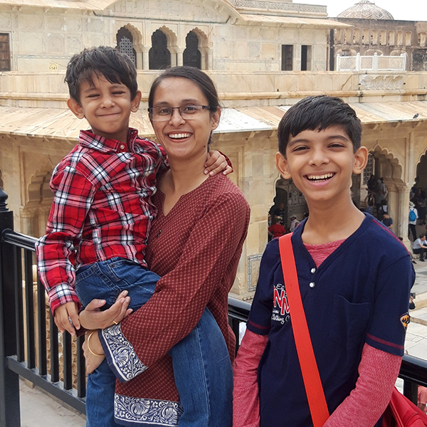 Anamika holds her younger son while her older son stands nearby