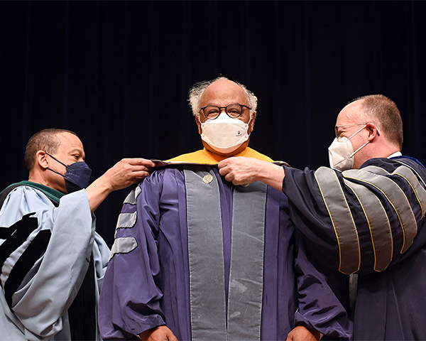 Dr. Jones and President DeGioia place a sash over Dr. Goosby