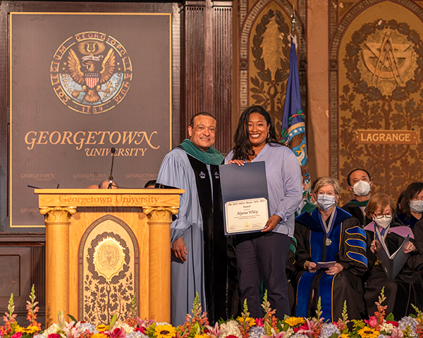 Holding her award, Alynna Willey stands next to Dean Jones onstage 