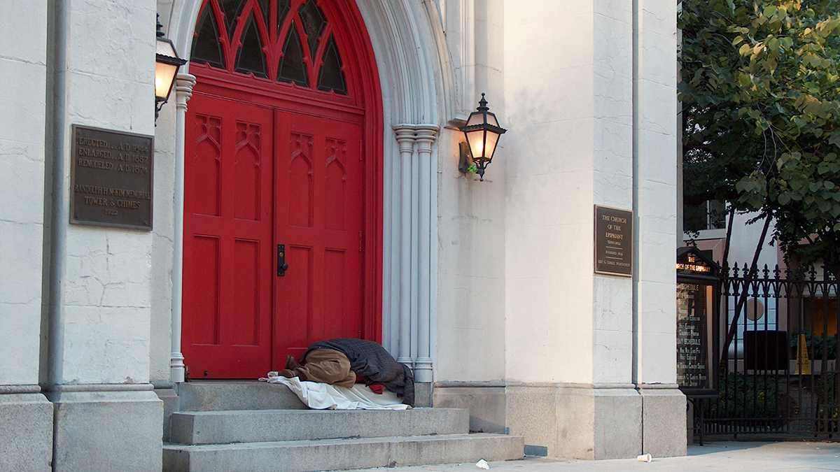An individual sleeps in the doorway of a church