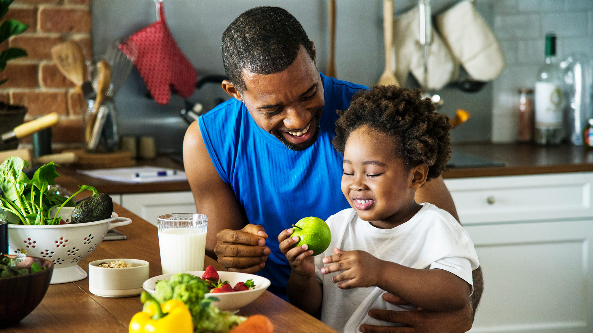 A man and his son share healthy foods in the kitchen