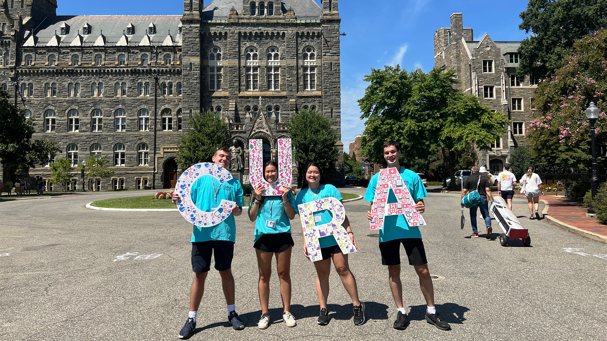 Four students hold the letter CURA