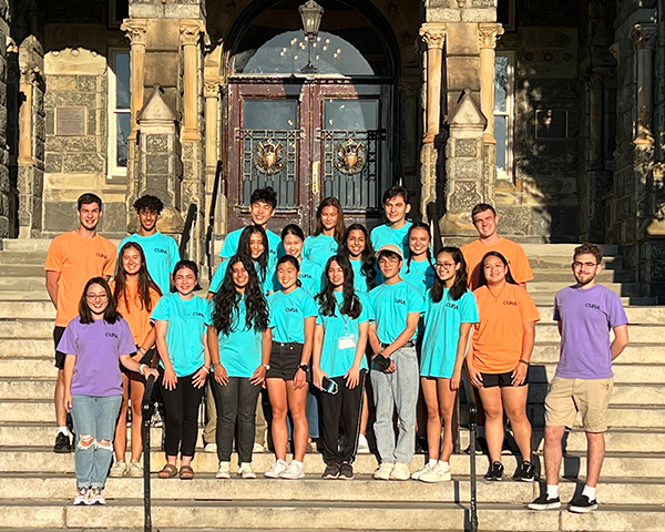 A group of students stand together on the steps of Healy Hall