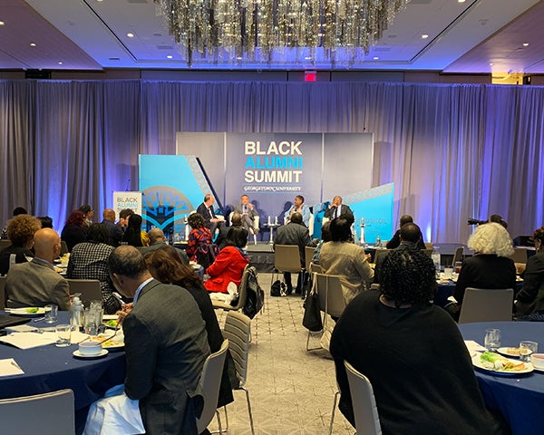 A view of the room with the panelists sitting onstage at the front