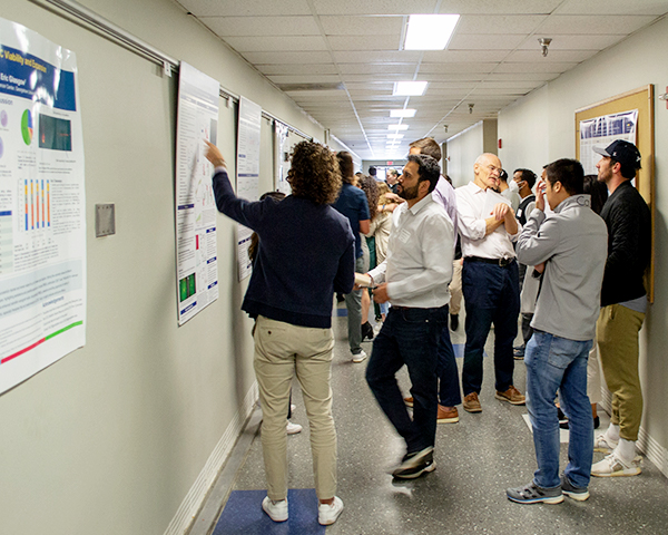 A hallway crowded with student presenters and professors rating them