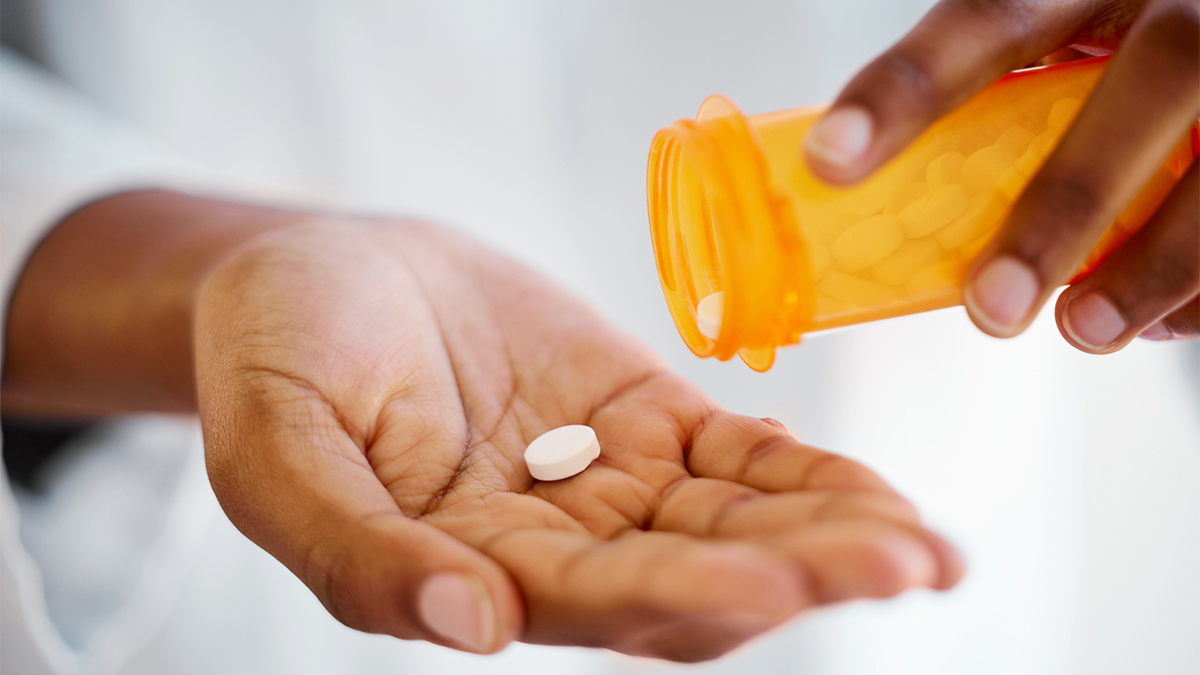 A person empties a pill from a bottle into their open palm