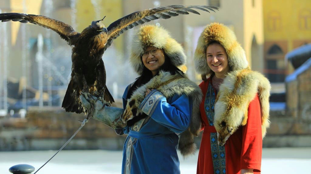Emily Ren stands with an eagle on her hand, next to her is another woman