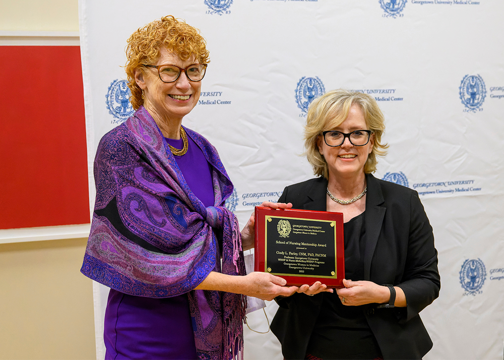 Eileen Moore and Sarah Vittone stand next to each other, each holding a corner of an awards plaque