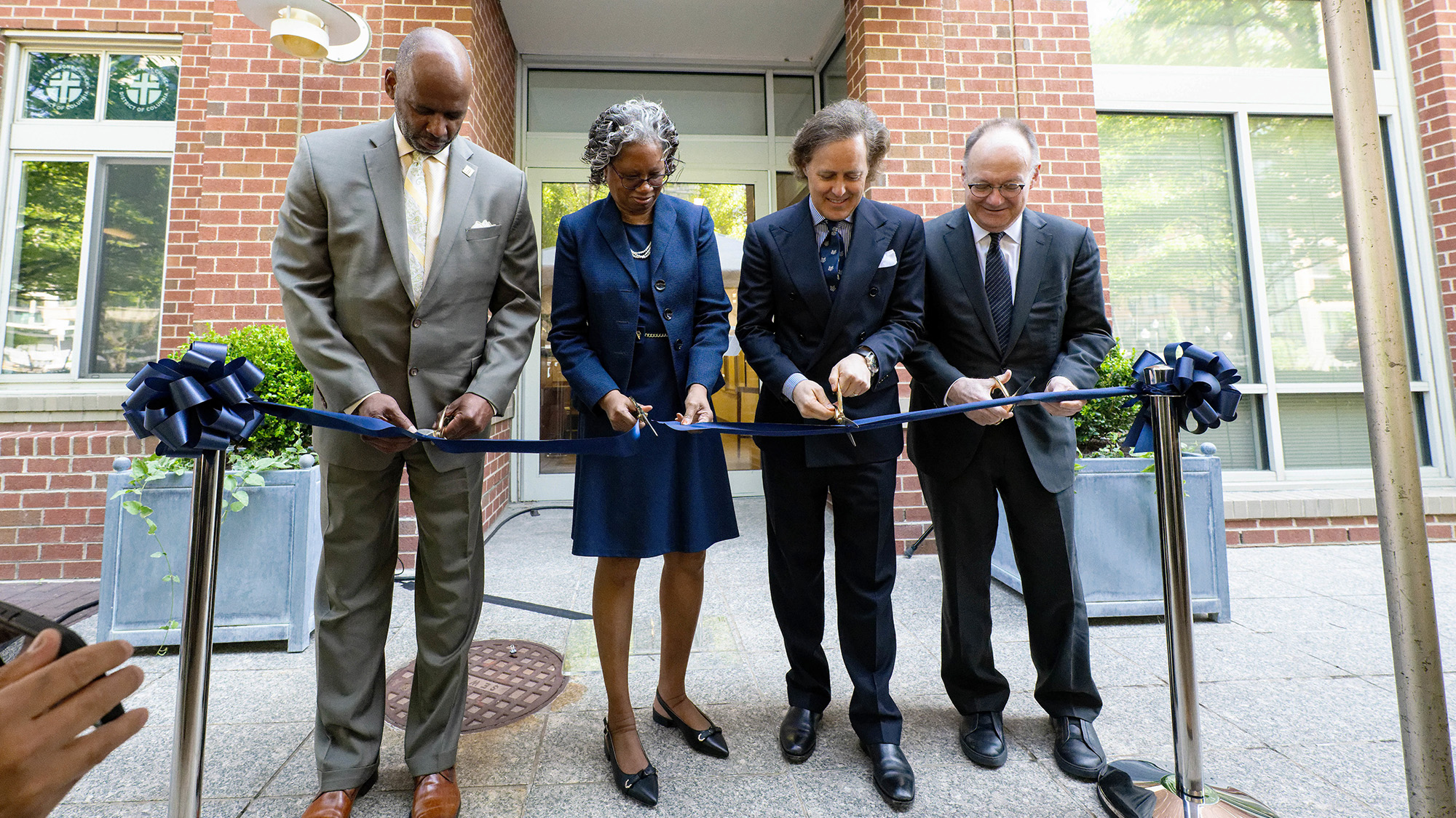 Four individuals cut a ceremonial ribbon in front of the Ralph Lauren Center for Cancer Prevention