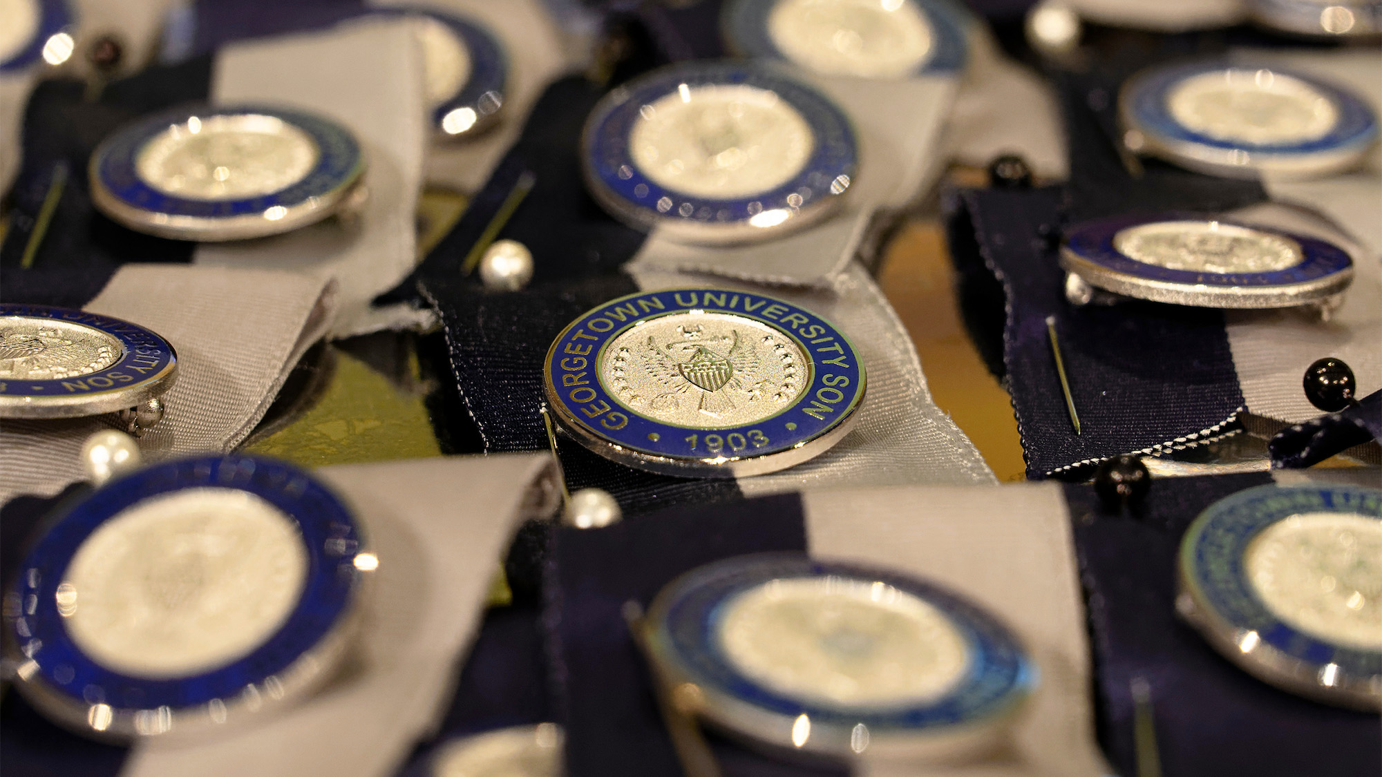 A collection of nursing pins attached to blue and white ribbons laid out on a tray