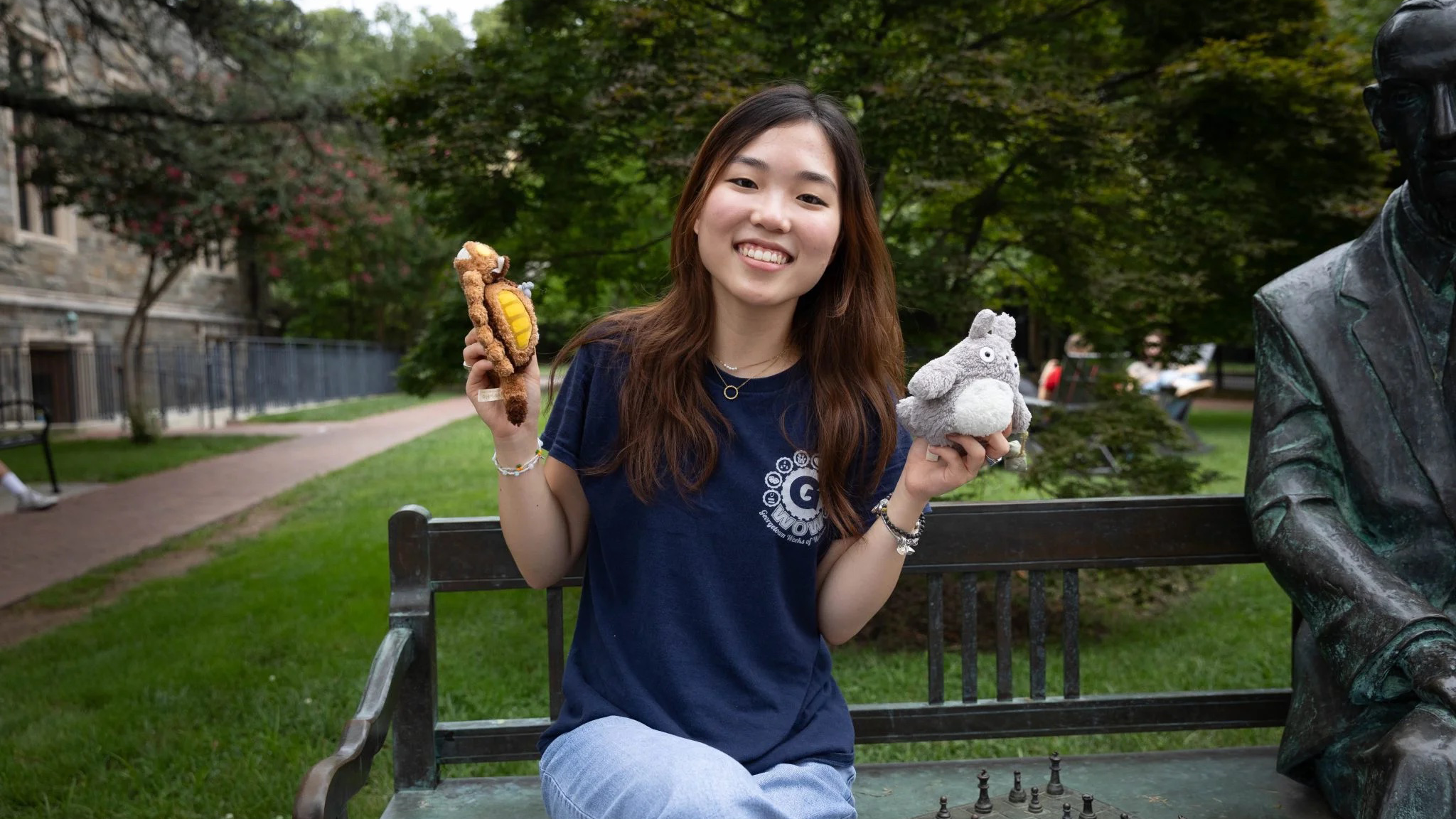 Ashley Jeong sits on a bench on campus holding stuffed animals