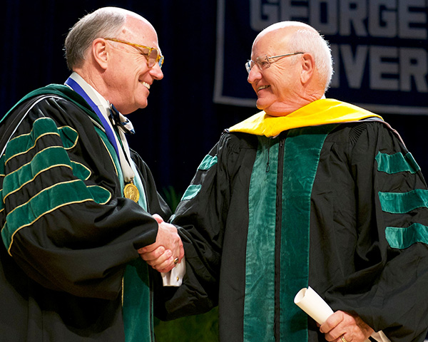 Dr. Mitchell shakes Dr. Ewy's hand at the ceremony