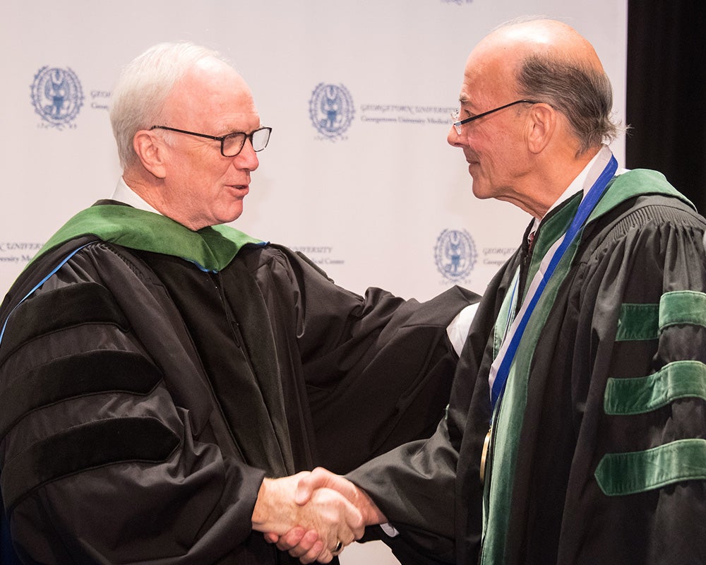 Dr. Healton shakes hands with a faculty member at convocation