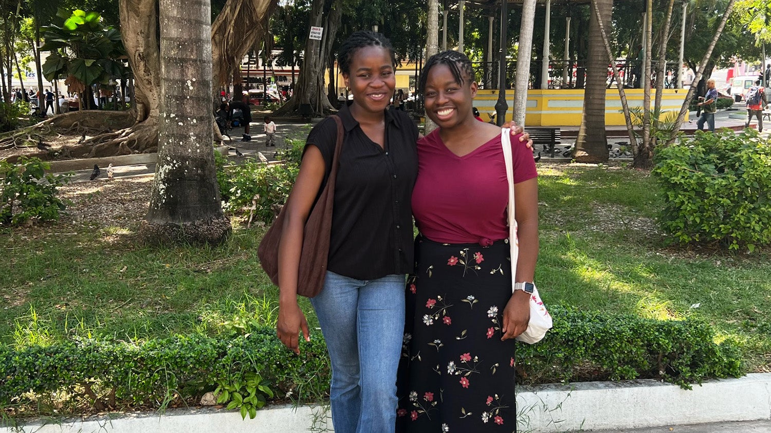 Students Phoebe Ato and Rukewe Kehinde stand next to each other in a parklike setting