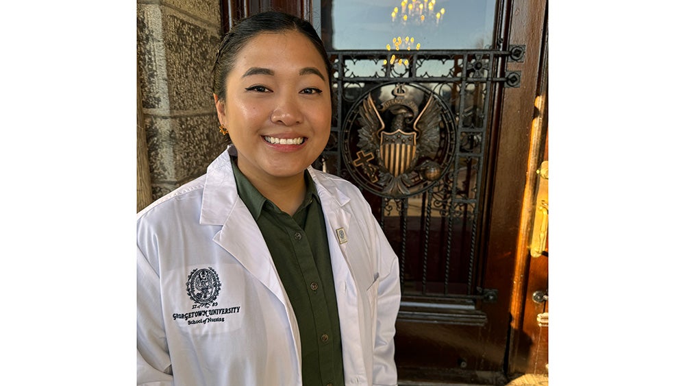 Jaclyn Sison pictured in her nursing white coat outside Healy Hall on campus