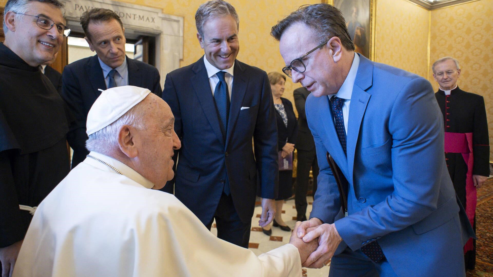 Norman Beauchamp grasps the hand of the Pope during a visit to the Vatican, while papal assistants look on