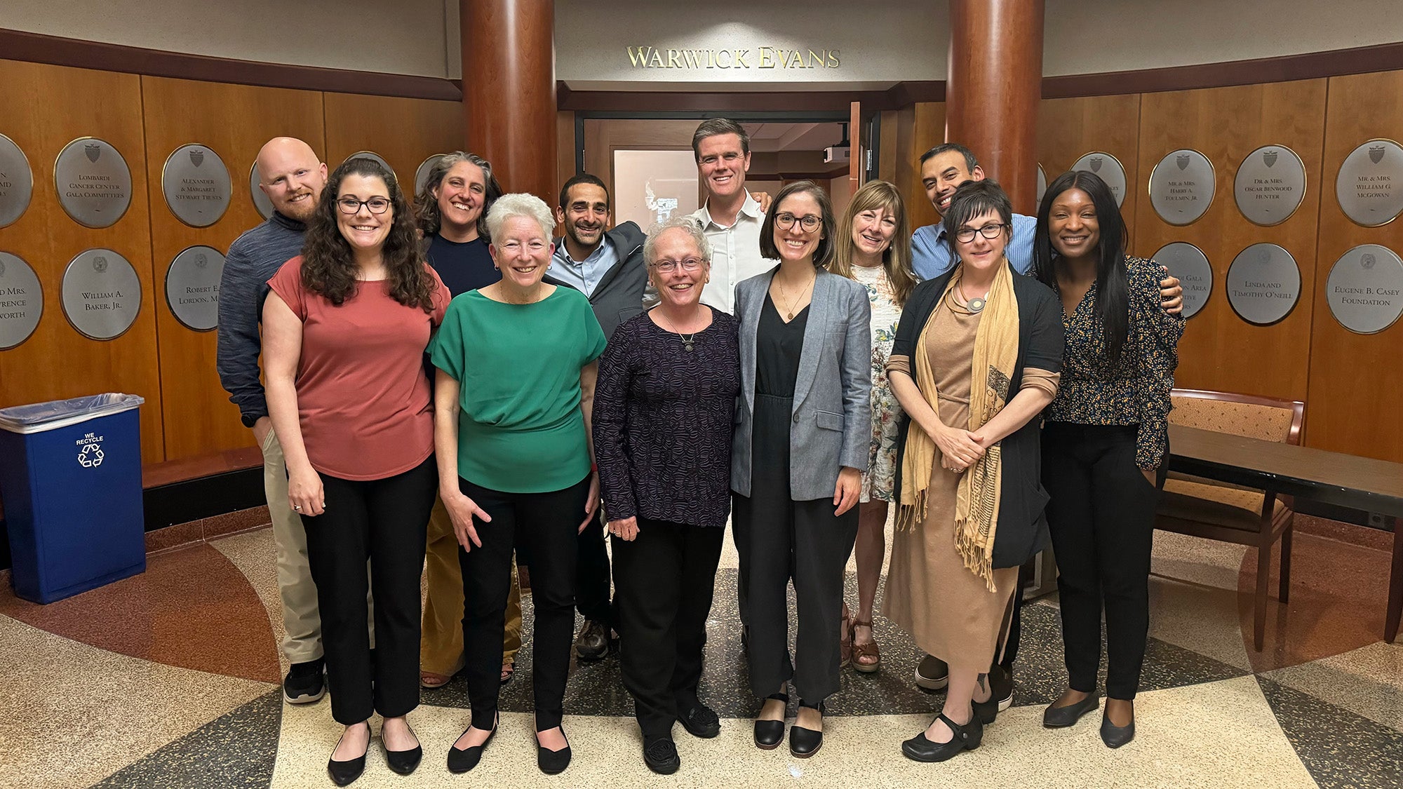 A group of people stand together in the lobby of Warwick Evans in Healy Hall