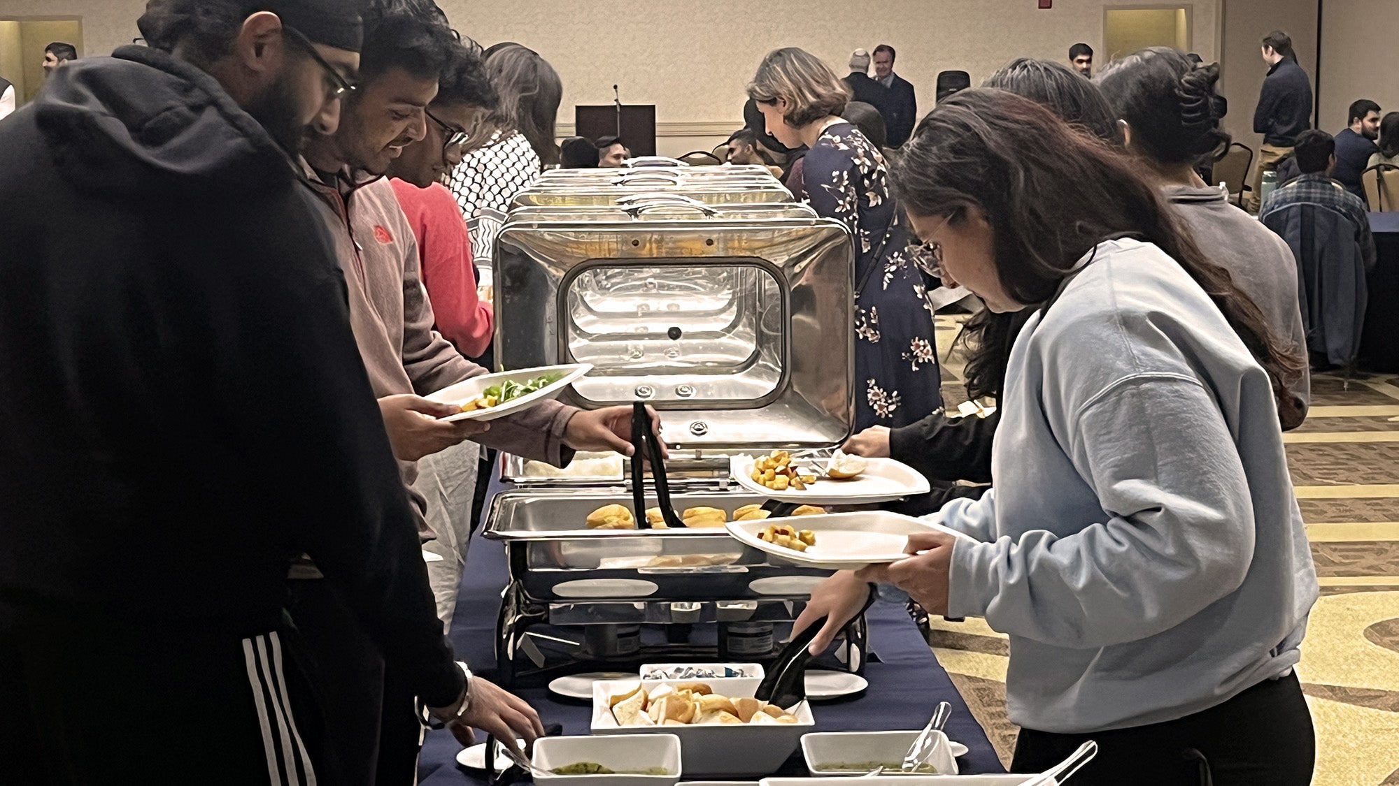 Students help themselves to food from chafing dishes set out on tables at the Interfaith Dinner